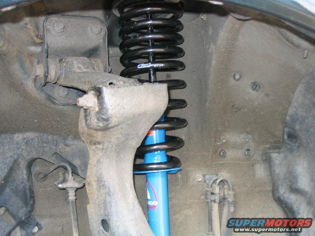 Close-up of a vehicle's front suspension with a blue shock absorber and black coil spring