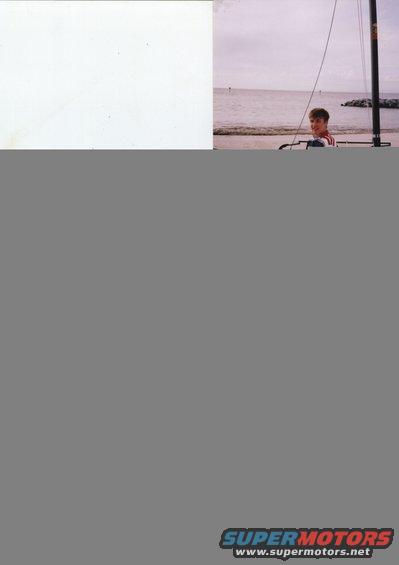 Boy in striped shirt on a sailboat mast at the beach