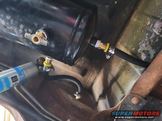 Underneath view of an aftermarket air tank and a Bilstein shock absorber mounted to vehicle frame
