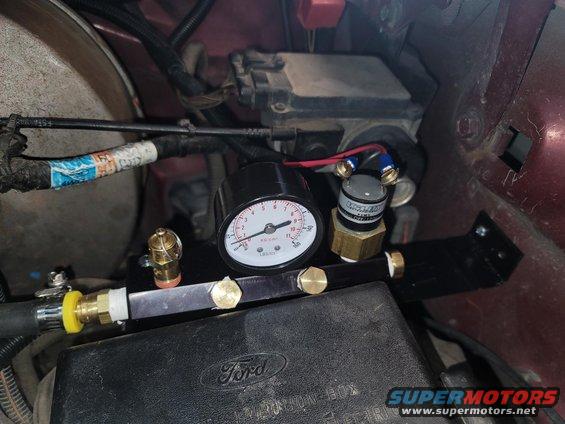 Close-up of an on-board air system gauge and brass fittings mounted near a Ford fuse box