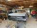 1967 Ford Mustang - A 1967 Ford Mustang body, prepped for paint, sits in a garage next to a vintage red truck.