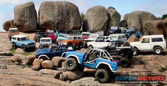 Several 1973 Ford Broncos parked on large rocks, some modified for off-roading