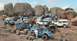 1973 Ford Bronco - Many off-road vehicles and people are gathered on a rocky terrain with large boulders in the background.