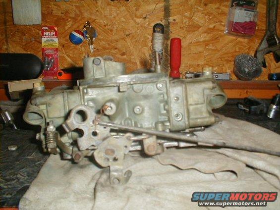 Carburetor on a workbench with tools and supplies in the background