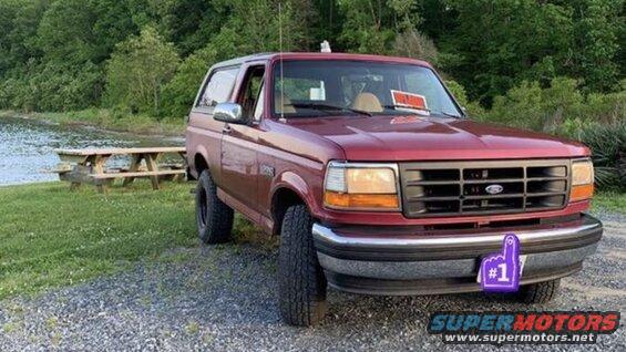 Red 1994 Ford Bronco with a 'For Sale' sign on the dash