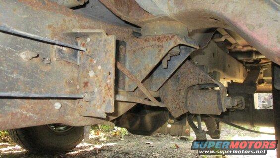 Underside of a rusty vehicle frame with suspension parts visible