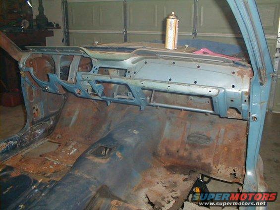 1967 Ford Mustang interior, showing rusted floor pans and a disassembled dashboard with a spray can on top