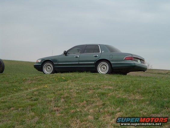 Green 1995 Mercury Grand Marquis parked on a grassy hill, side view