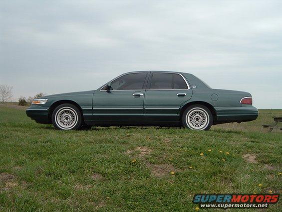 1995 Mercury Grand Marquis sedan, side view, parked on a grassy hill