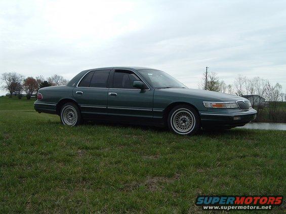 Green 1995 Mercury Grand Marquis parked on a grassy field with trees in the background