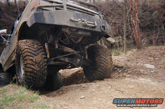 Muddy off-road vehicle with large tires going over rough terrain