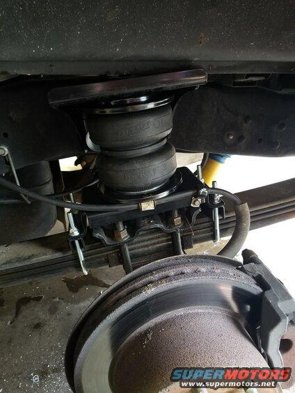Close-up of air suspension helper bags installed on the rear axle of a truck, near the brake rotor