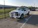 2008 Ford F-250 - A white 2008 Ford F-250 pickup truck is parked in a lot, with another vehicle on a trailer in the background.
