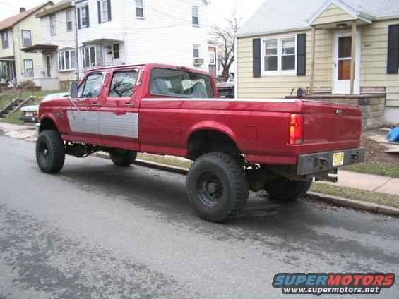 Red crew cab pickup truck, lifted, with silver side trim