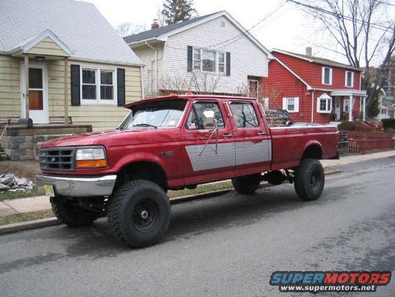 Red crew cab pickup truck with silver side paneling and large tires