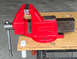 2002 Ford Ranger - A red vise with black accents is mounted on a wooden workbench, ready for use.