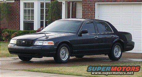 Black sedan parked in front of a garage, showing its front and side profile
