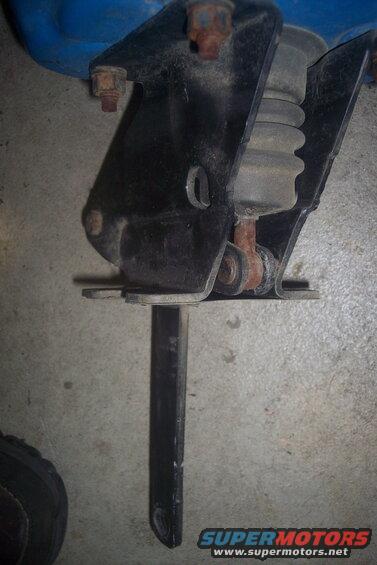 Black metal suspension part with rubber bellows and rusty bolts against a concrete floor