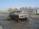 1979 Ford Bronco - This 1978 Ford Bronco is navigating a challenging muddy terrain with industrial fencing and structures visible in the distance.
