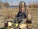 1979 Ford Bronco - A man is seated in a yellow dune buggy, parked on a sandy bank near dry reeds and water.