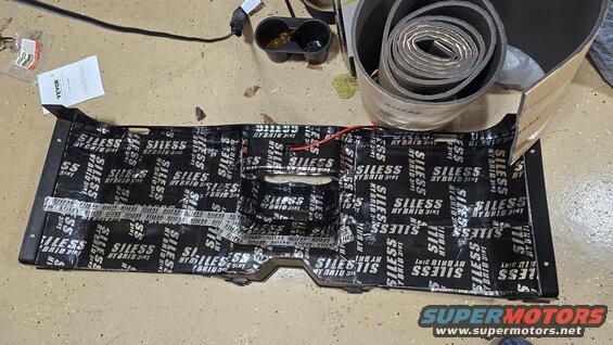 Center console panel covered in black sound dampening material with white text
