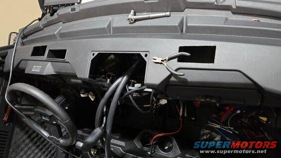 UTV dashboard with open compartments showing wiring, steering wheel, and tools