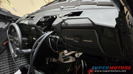 Black dashboard and steering wheel of a vehicle with exposed wiring and components
