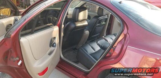 Red sedan's interior showing front and back seats. Driver's side front door and rear passenger door are open