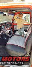 Orange truck interior with a child standing on the seat, showing a steering wheel and dashboard