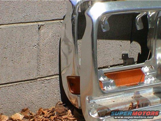 Chrome grille and orange turn signal assembly against a brick wall