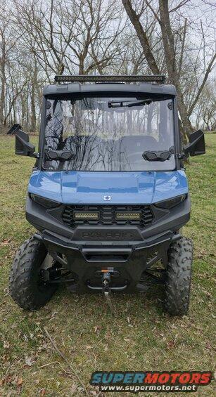 Front view of a blue Polaris side-by-side with a light bar on top and LED lights on the bumper