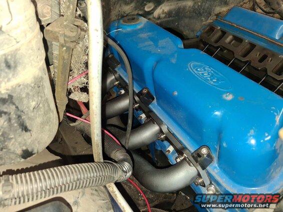 Close-up of a blue Ford valve cover with exhaust headers attached