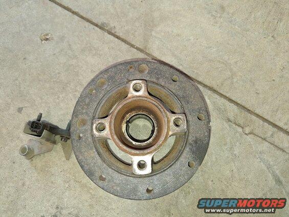 Crankshaft pulley with a sensor attached, lying on a concrete surface