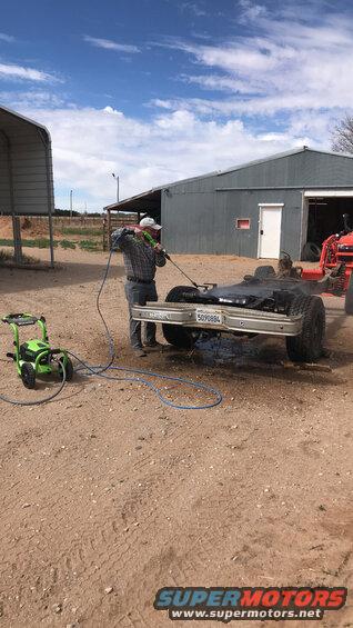 guy pressure washing a vehicle frame with a license plate that reads 5070884