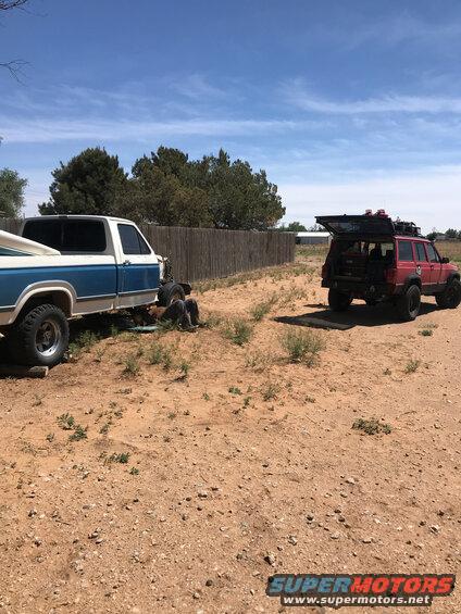 Blue and white pickup truck next to a red Jeep Cherokee with its rear hatch open