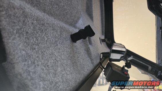Interior shot of a vehicle cabin, showing grey fuzzy lining and a black clip. A side mirror and control panel are visible