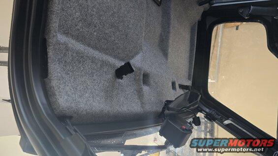 Interior of a vehicle with gray carpeted walls and black trim. A black control lever is visible