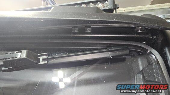Black windshield wiper assembly and light bar mounted above windshield