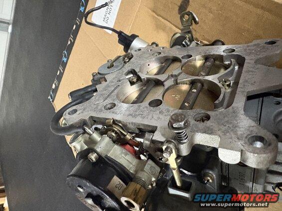 Close-up of a carburetor with visible linkages and throttle plates