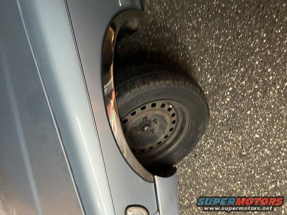Close-up of black steel wheel and tire on a gray car over asphalt