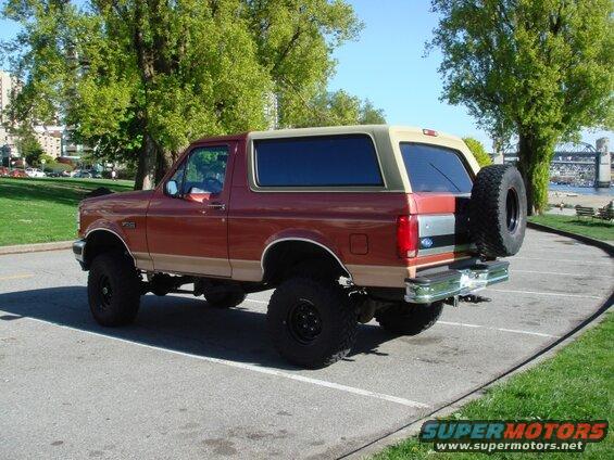 Lifted red and tan Ford Bronco parked outdoors.