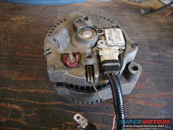 Overhead view of a used Ford alternator on a wooden surface.