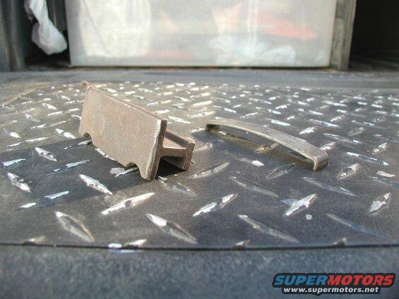 Two metal parts on a black diamond plate surface.