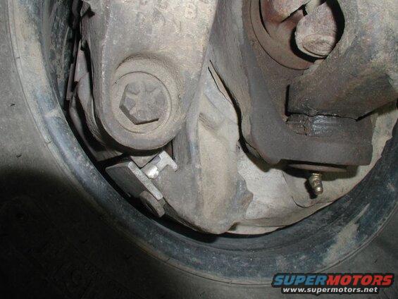 Close-up of vehicle brake assembly with pads, bracket, and grease fitting.