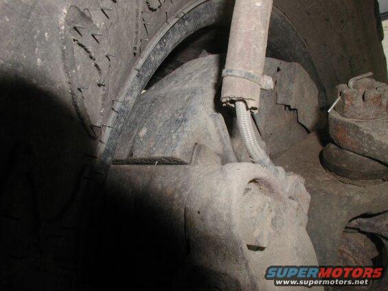 Close-up of a dirty tire, shock absorber, and lug nut on a vehicle.