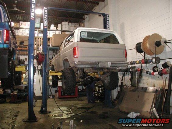 1985 Ford Bronco on a rotary lift in a workshop.