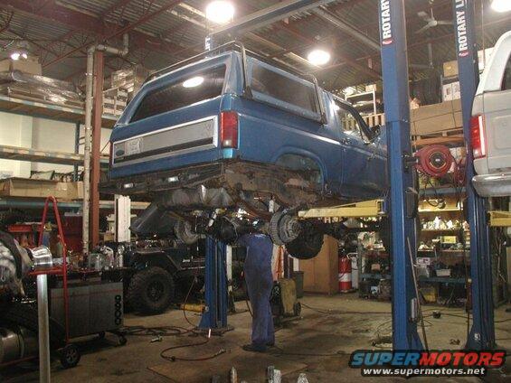 Blue 1985 Ford Bronco on a lift in a garage.