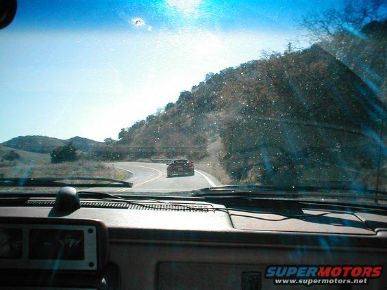 Red sports car seen from inside another vehicle on a winding road