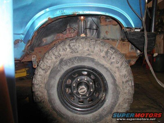 Close-up of rusty rear wheel well of a blue Ford Bronco.