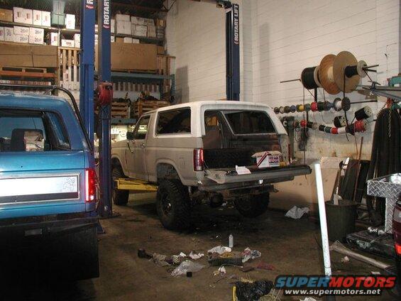 1985 Ford Bronco on a car lift in a garage, rear hatch open.